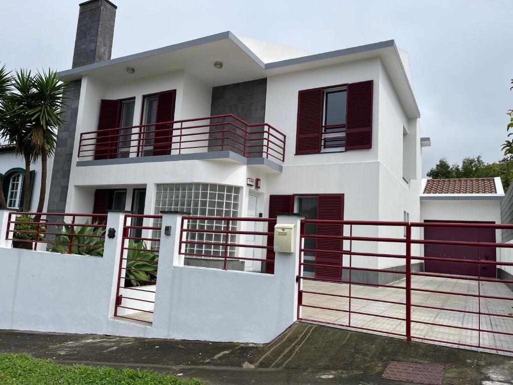 una casa blanca con barandilla roja y una puerta en Populo Beach Villa, en Livramento