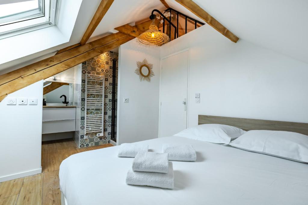 a bedroom with a white bed with towels on it at T2 cosy et chic près de la Défense et de Paris in Maisons-Laffitte