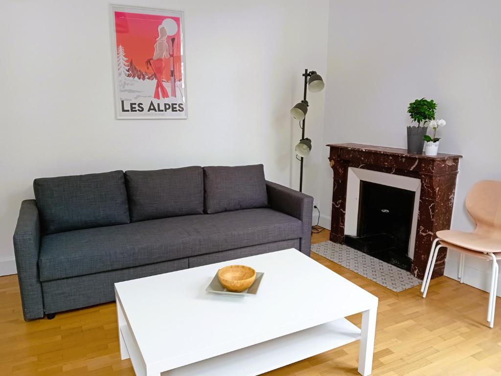 a living room with a couch and a table at Appart rénové avec grand salon et 1 chambre - Tram et Clinique Mutualiste à 1 min in Grenoble