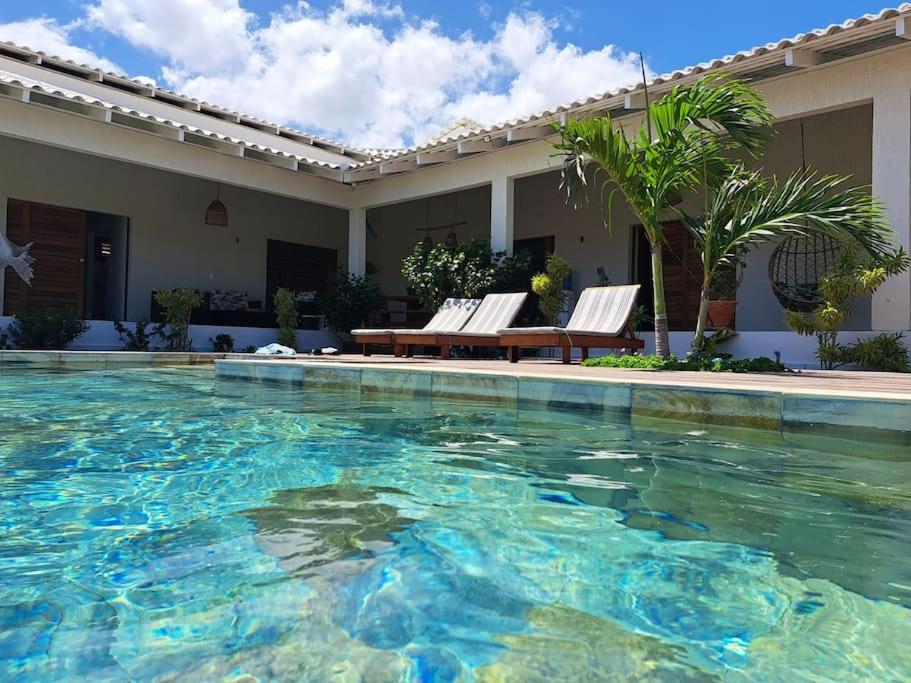 uma piscina com duas cadeiras e uma mesa em Casa charmosa na Barrinha (Prea) perto da Praia em Acaraú