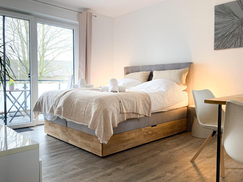 a bedroom with a bed and a large window at PEARLs - Stilvolle Neubauwohnung am Niederrhein in Elten