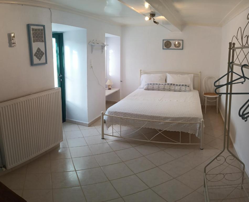a white bedroom with a bed and a tiled floor at Το σπιτάκι στον παραδοσιακό οικισμό Λειβαδίων Άνδρου in Vrakhnós