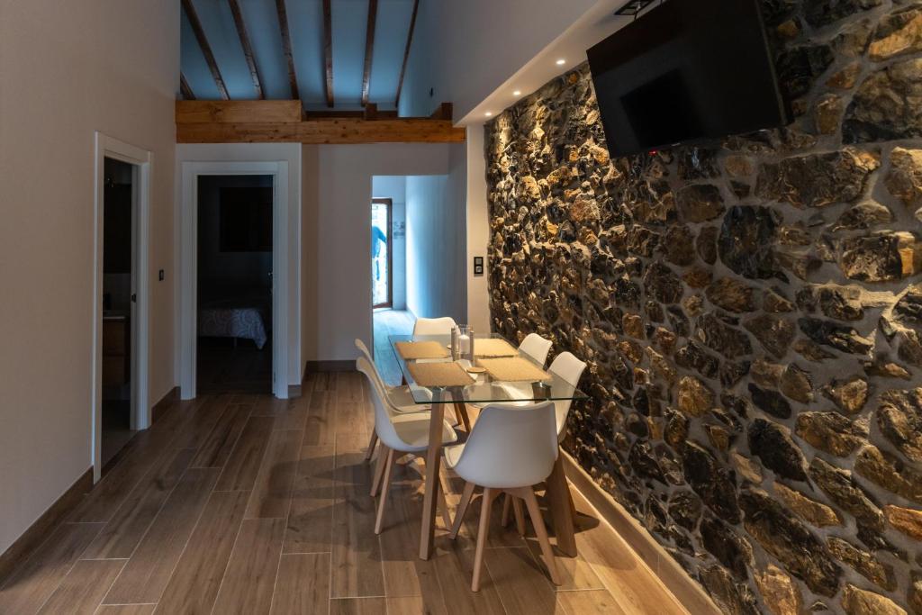 a dining room with a stone wall and a table and chairs at Apartamentos Iramar in Ramales de la Victoria