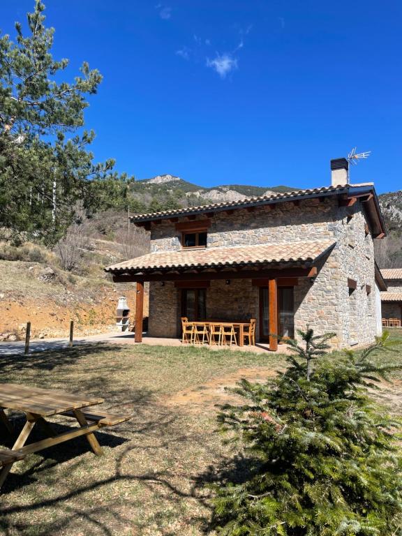 una casa de piedra con una mesa de picnic delante de ella en Casa de la Mestra, Espinalbet - ALBERGA, en Castellar del Riu