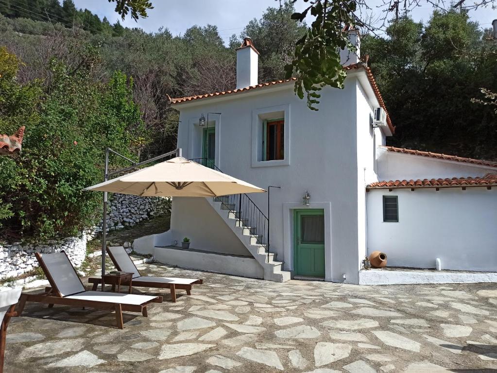een wit huis met twee stoelen en een paraplu bij Casa de la Fuente in Ditropo
