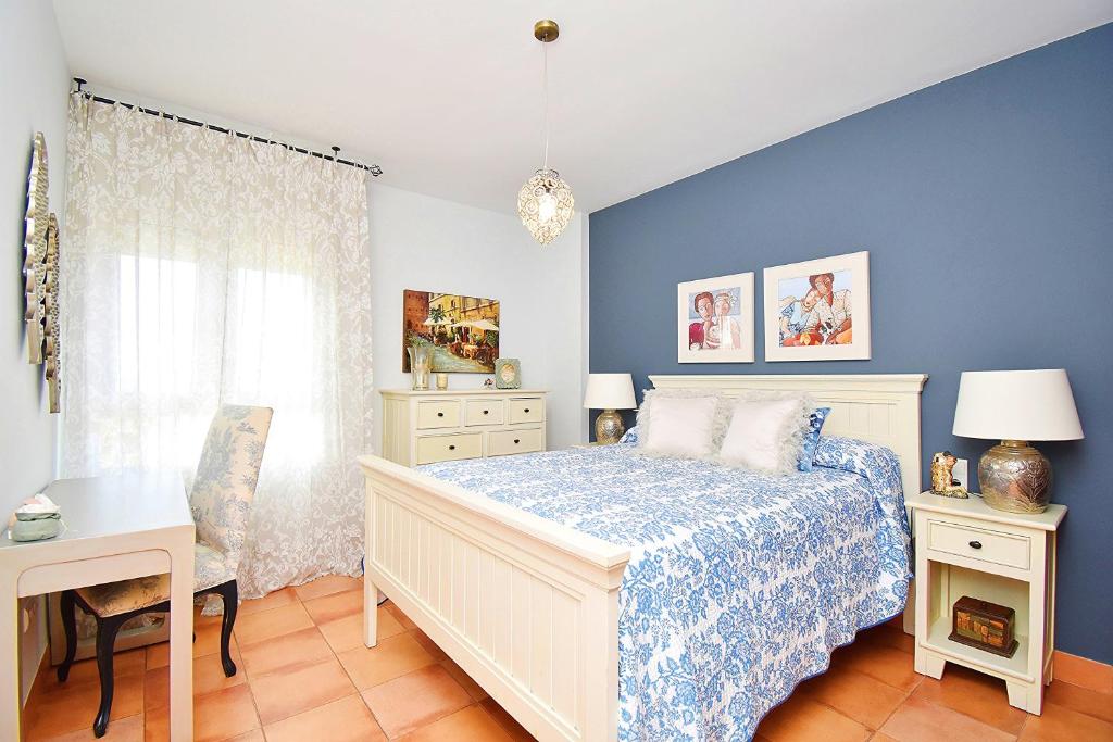 a bedroom with a bed and a blue wall at EXPOHOLIDAYS - Vistas al mar playa ensenada in Almerimar