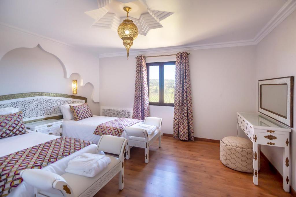 een hotelkamer met 2 bedden en een televisie bij Al Karob Yoga Boutique Hotel in Guia