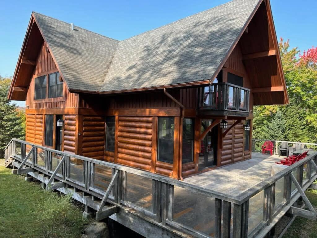 a large wooden cabin with a large deck at Captivating view of Lake Superieur in Lac-Superieur