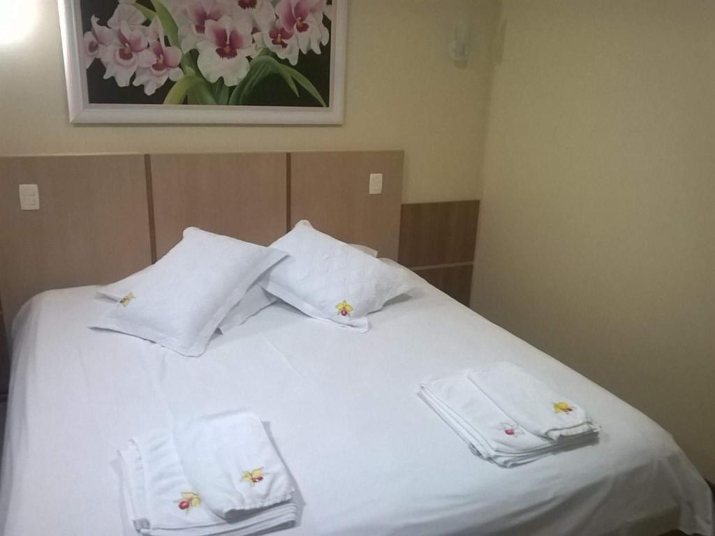 ein weißes Bett mit zwei weißen Handtüchern darauf in der Unterkunft Pousada Paraíso das Orquídeas in Nova Santa Medianeira