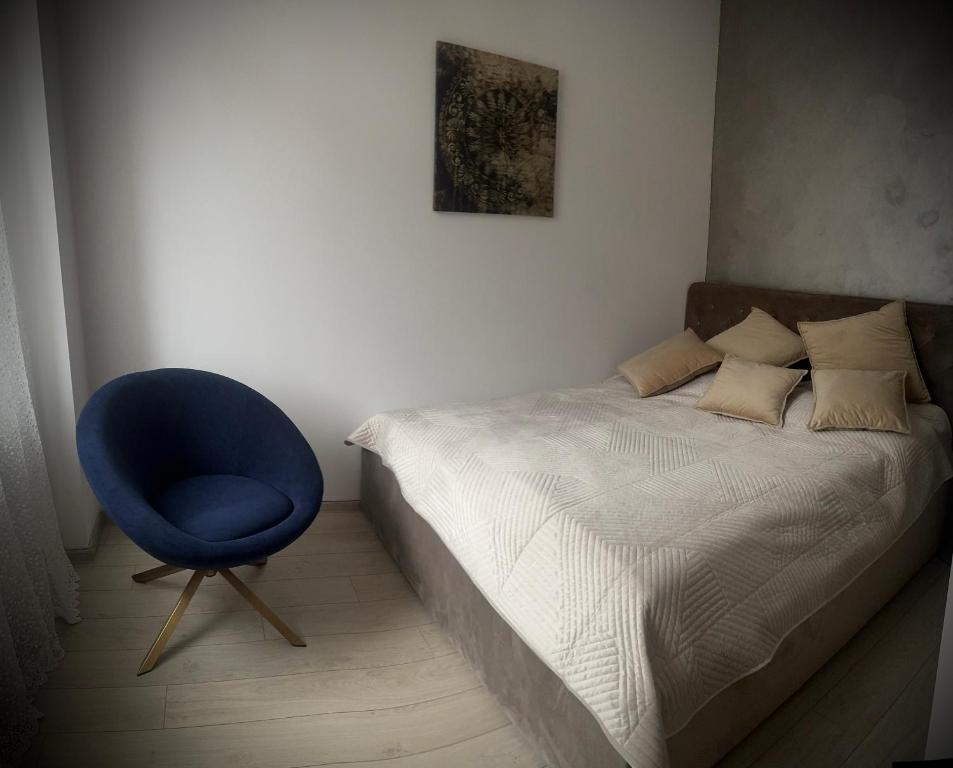 1 dormitorio con 1 cama y 1 silla azul en Apartament Nowar, en Nowa Ruda