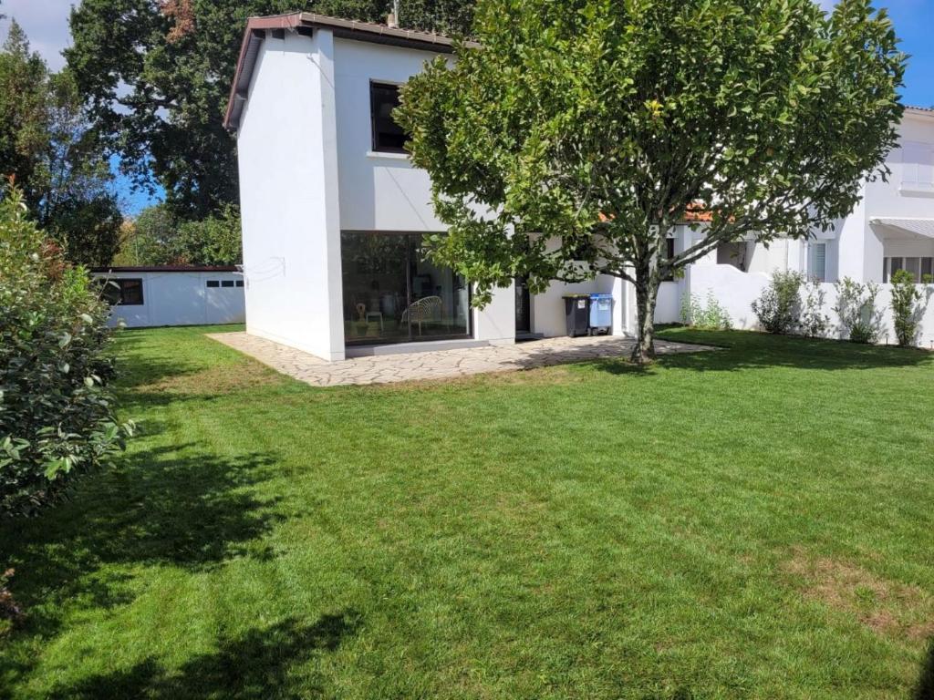 une maison dotée d'une cour verdoyante avec un arbre dans l'établissement Jolie maison 3 chb et jardin proche Arcachon, à La Teste-de-Buch