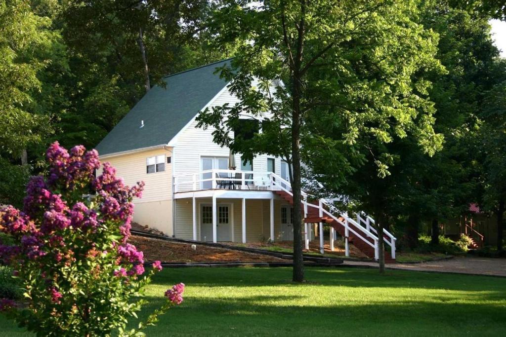 Cette maison blanche dispose d'une terrasse couverte et d'un balcon. dans l'établissement River Ridge Inn, à Norfork