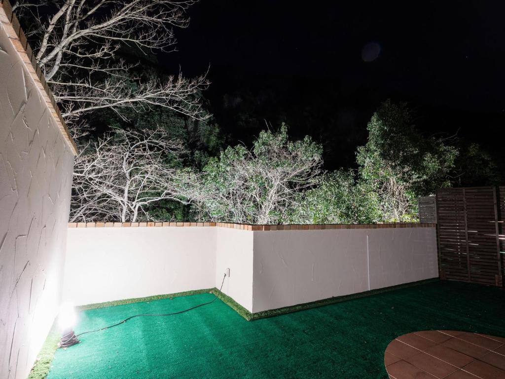 a backyard with a white fence and trees at night at Riverside Glamping Kamiseno - Vacation STAY 92757v in Hiroshima