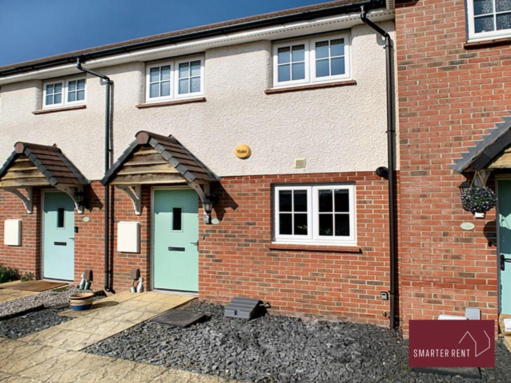 a brick house with green doors and a courtyard at Jennett's Park, Bracknell - 2 Bedroom Home in Bracknell