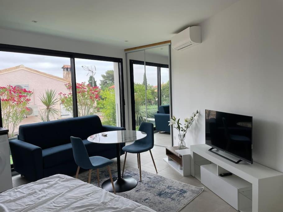 sala de estar con sofá y mesa con sillas en Studio familial centre ville, Parc expo, Arena en Pérols