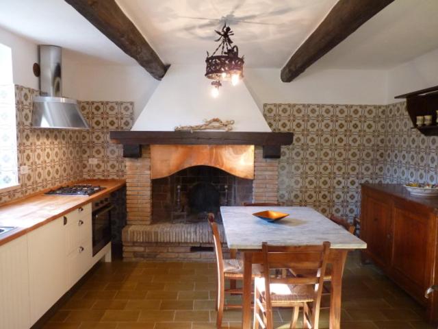 a kitchen with a fireplace and a table and chairs at Casa Asia in Castiglione della Pescaia