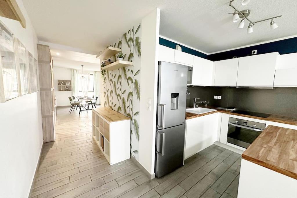 une cuisine avec des armoires blanches et un réfrigérateur noir dans l'établissement Bel Appart Design 2ch, Mairie, Pkg, Wifi, Terrasse, Port Marianne, à Montpellier