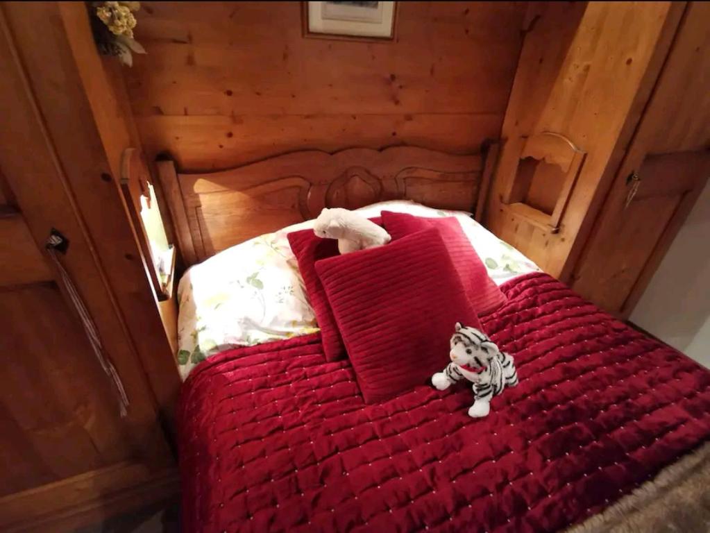 ein rotes Bett mit einem ausgestopften Tier darauf in der Unterkunft La terrasse du mont Blanc in Cordon