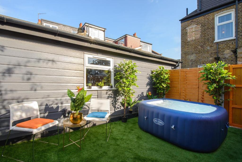 un patio trasero con una gran bañera azul sobre el césped en Impeccable 1-Bed Apartment in London en Londres