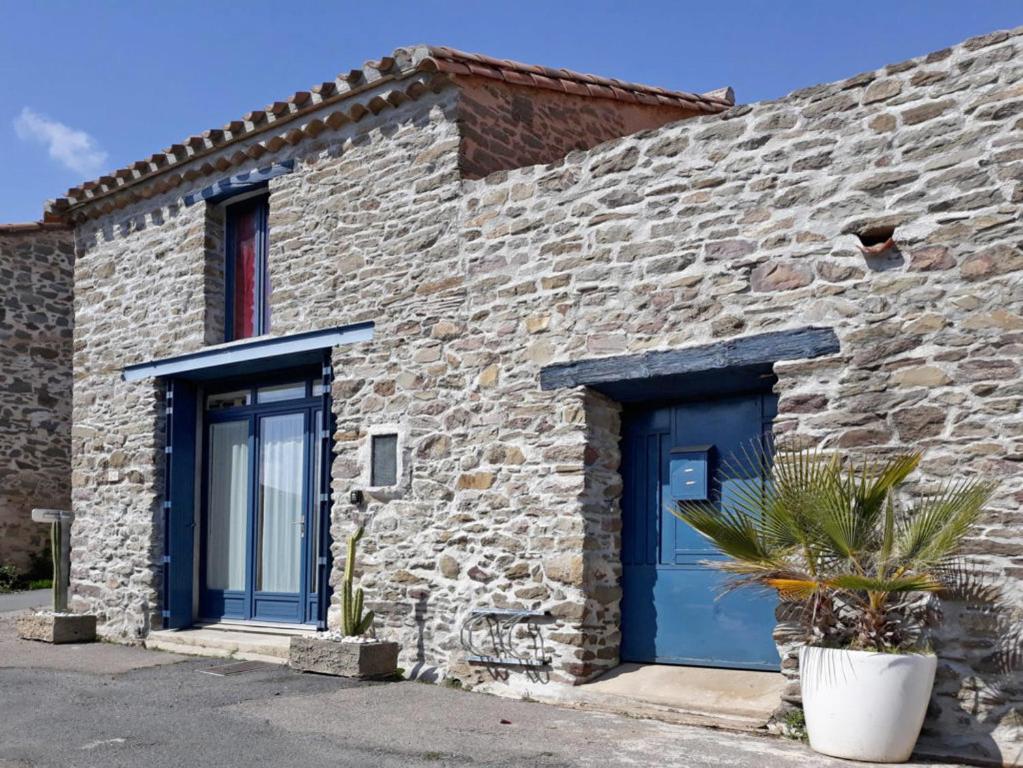 um edifício de pedra com uma porta azul e uma planta em Opuntia Teouliero location en Méditerranée em Escales