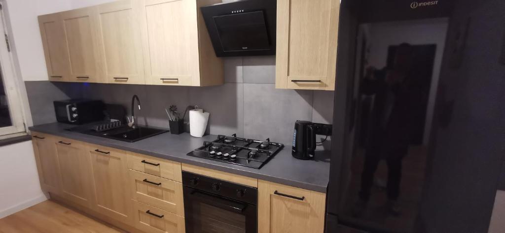 eine Küche mit Holzschränken und einem schwarzen Kühlschrank in der Unterkunft Apartament Wojska Polskiego in Starachowice