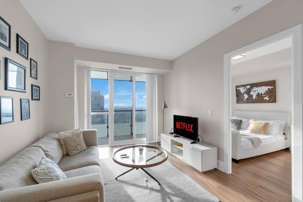 uma sala de estar com um sofá, uma televisão e uma cama em Rare 1BR - Rooftop Pool, Next to MTCC & CN Tower em Toronto