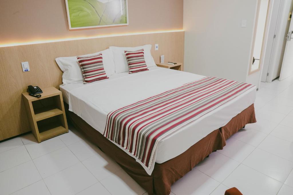 een slaapkamer met een groot bed en een gestreepte deken bij SLZ Lagoa Hotel in São Luís
