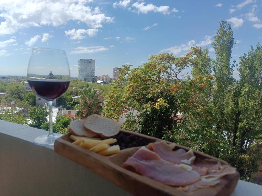 a glass of wine and a tray of meat and cheese at Del Parque, vista panorámica in Villa Marini