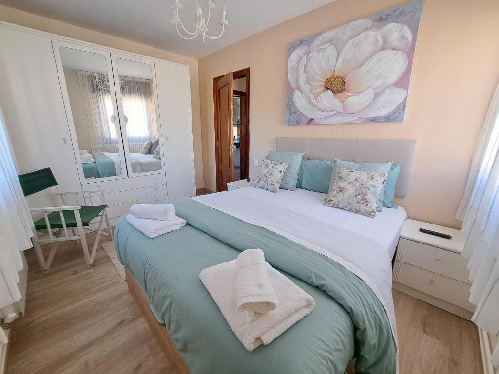 a bedroom with a large bed with a flower painting on the wall at Mi casita del norte in Mogro