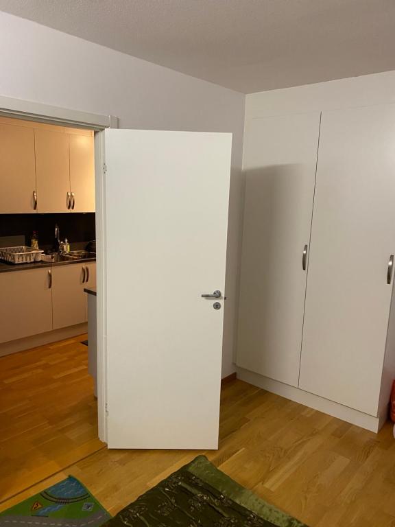 a white door in a room with a kitchen at Cozy room in a shared apartment close to nature in Gothenburg