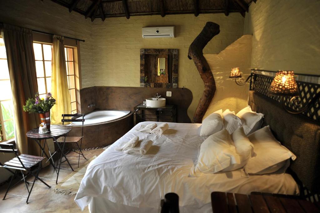 a bedroom with a large bed and a bath tub at African Silhouette Guesthouse in Benoni