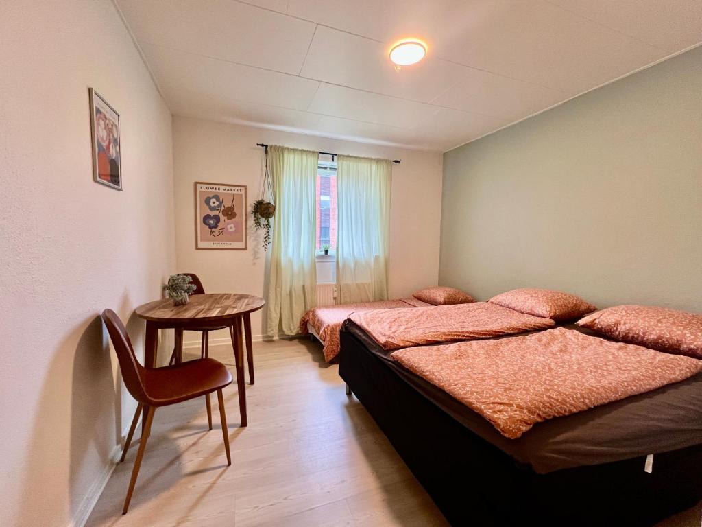 een slaapkamer met 2 bedden en een tafel met een stoel bij 5 minute walk to LEGO HOUSE - Best location-Garden on site-n3 in Billund