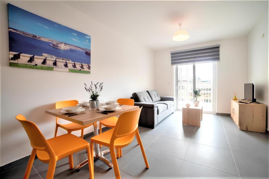 a living room with a table and chairs and a couch at Elise Apartments in Il-Gżira