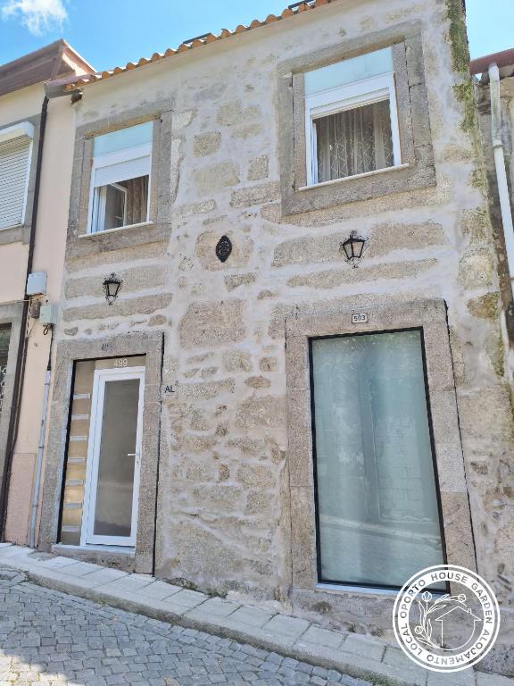 a stone building with two windows on a street at Oporto House Garden in Porto