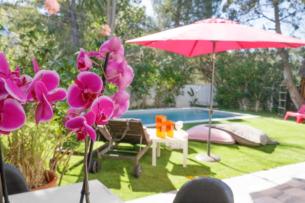 einen Tisch mit Blumen und einem Sonnenschirm neben einem Pool in der Unterkunft Dreamy relaxing secluded Villa Aurora in Palaia Fokaia