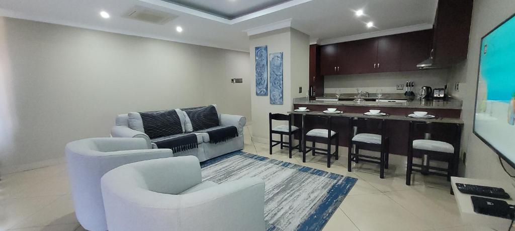 ein Wohnzimmer mit weißen Stühlen und eine Küche in der Unterkunft Accommodation Front - Relaxing 2 Sleeper near Ushaka Marine World in Durban