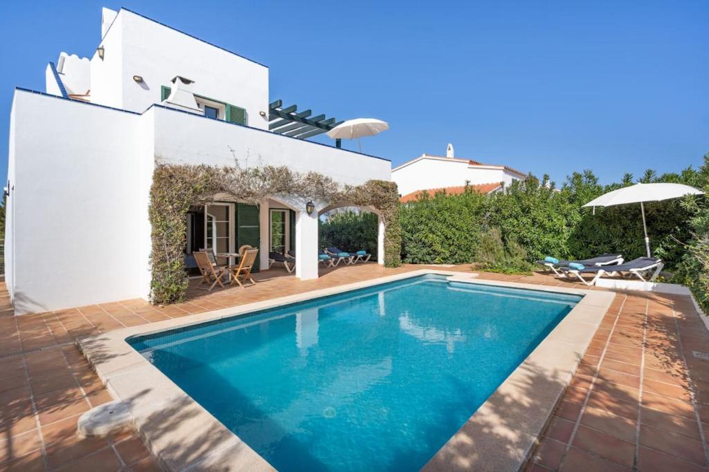 a villa with a swimming pool in front of a house at Villa Sea Garden Holidays in Port d'Addaia