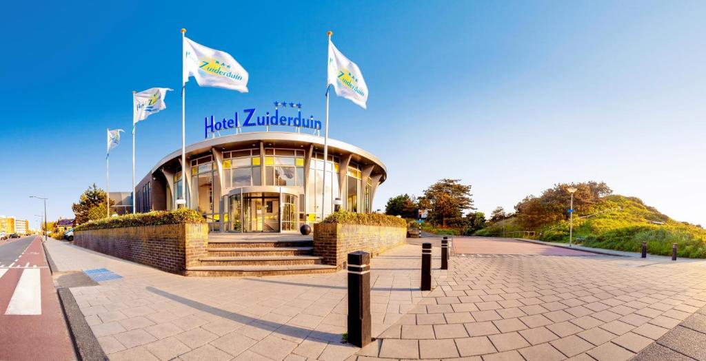 een groot gebouw met vlaggen ervoor bij Hotel Zuiderduin in Egmond aan Zee