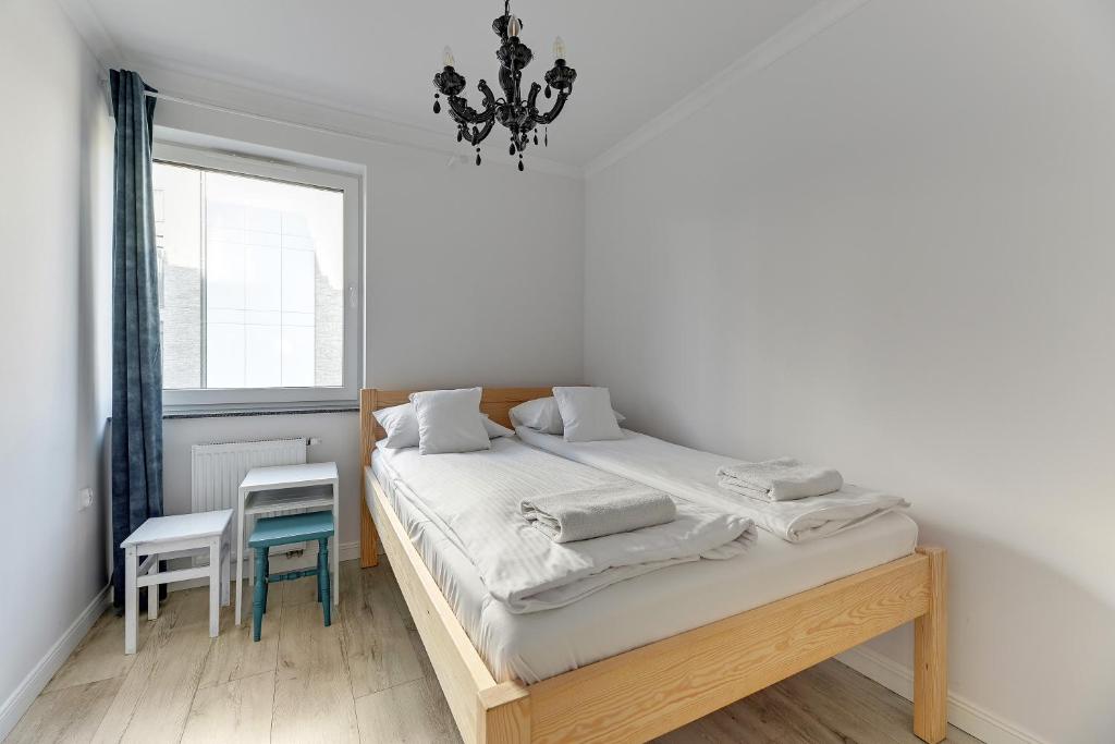 um quarto com uma cama, uma janela e um lustre em Grobla Centrum 2 by Grand Apartments em Gdansk