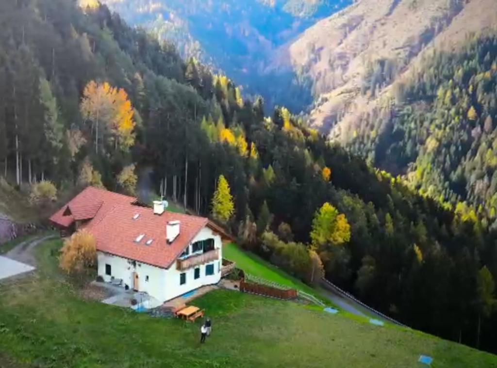 a house with a red roof on a green field at Masches in Funes