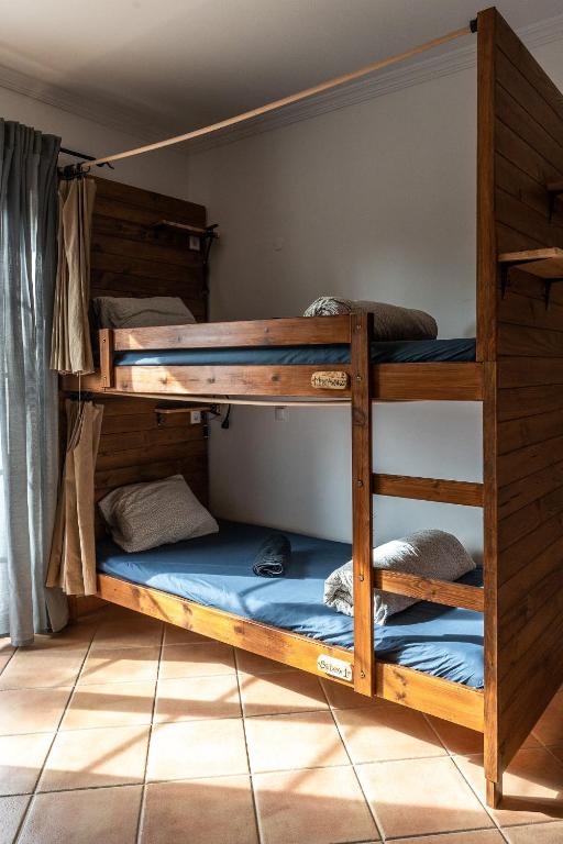 two bunk beds in a room with blue sheets at Aldeia Caiçara Surf House in Sagres