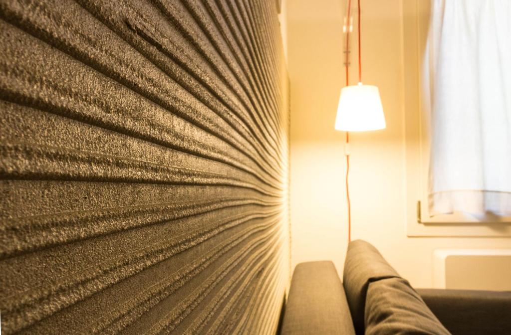 a couch in a room with a lamp and a curtain at Biciclò Mini Studio in Ferrara