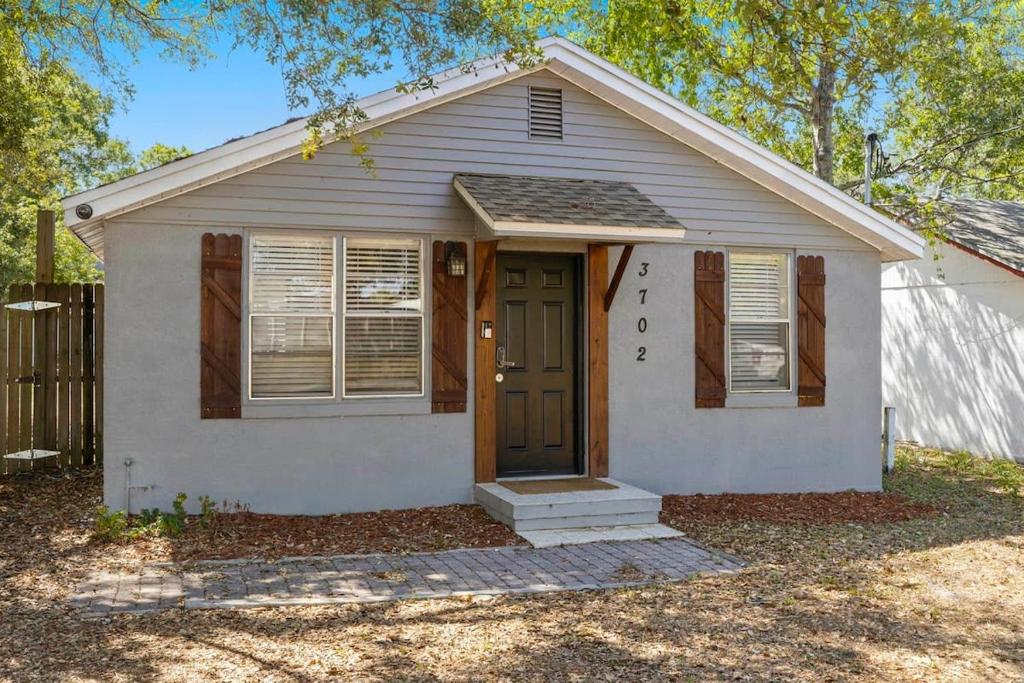 una pequeña casa con una puerta marrón en un patio en Entire House~Huge Backyard~Sleeps 5~ 3 beds 2 bath, en Tampa