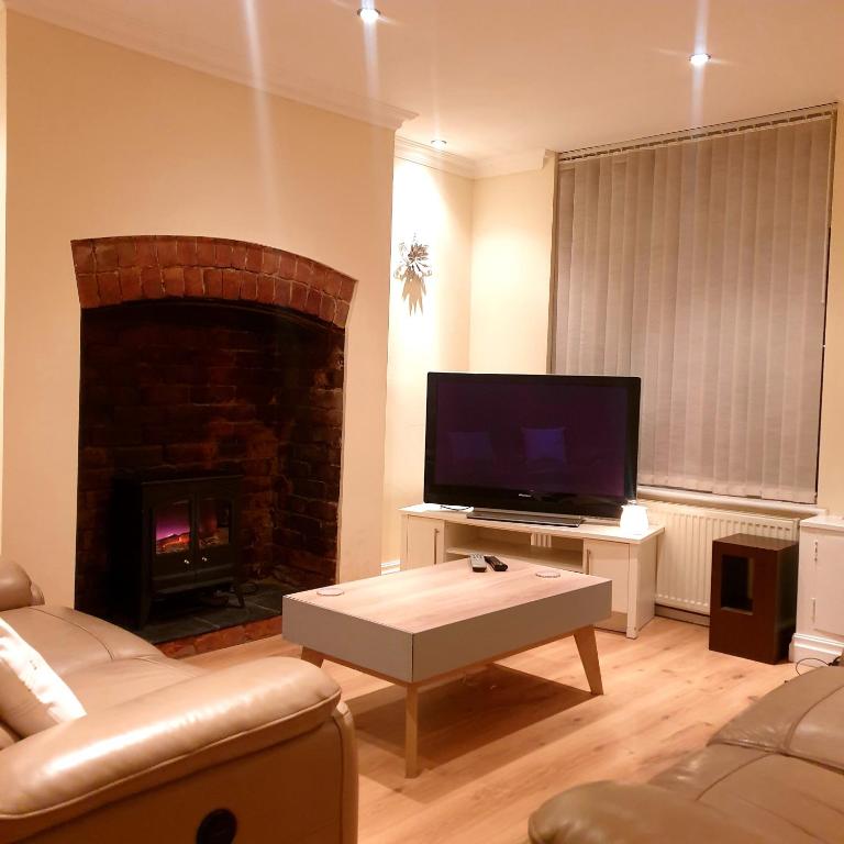 sala de estar con TV y chimenea en Carter House, en Bradshaw