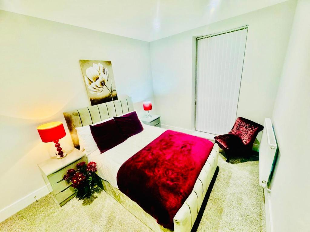 a bedroom with a large bed with a red blanket at Icare Lodge Ltd,Safwaan House. in Barking