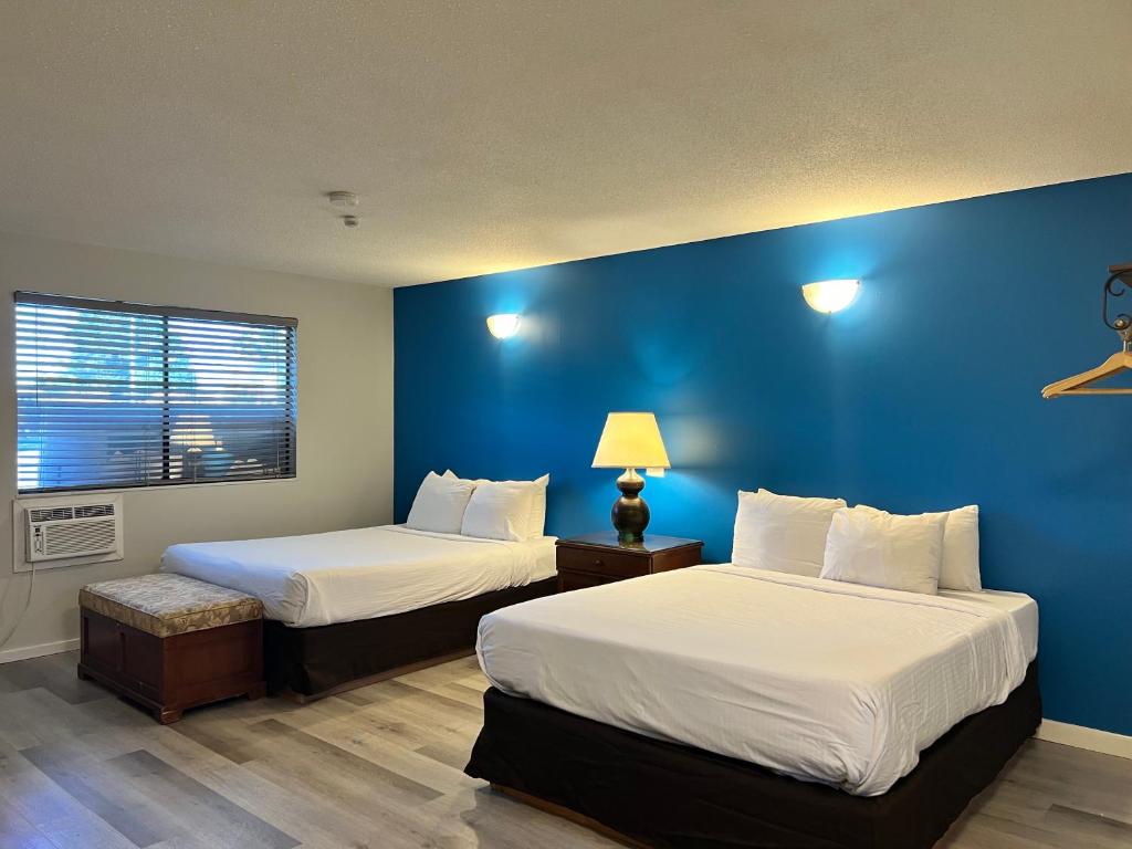 two beds in a room with blue walls at VIP Motel in Parksville