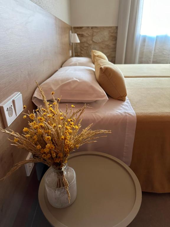 a bedroom with a bed with a vase of flowers on a table at Hostal Barris in Pals