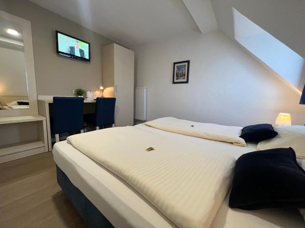 a bedroom with a bed and a desk with a television at Hotel Pelikan in Kitzingen