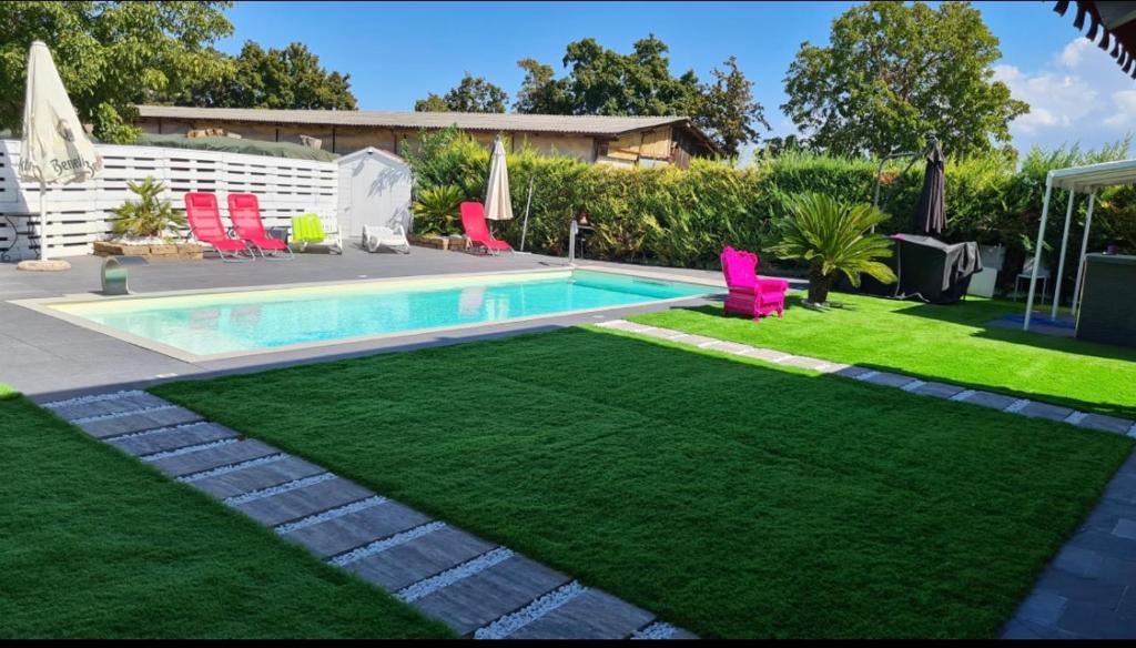 un patio trasero con piscina y césped verde en B&B le palme en Castel Maggiore