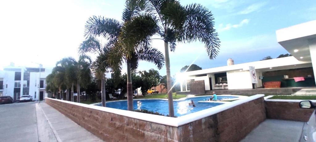 een zwembad met palmbomen voor een gebouw bij Departamento Puerta Dorada in Manzanillo